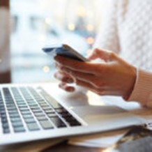 hands holding a phone with laptop