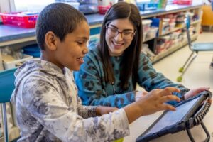 Student looking at book with teacher