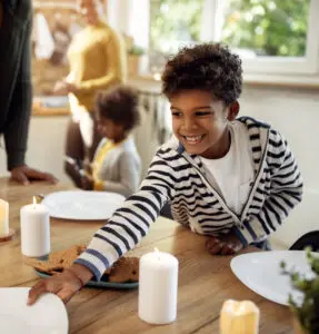 A smiling boy is setting the table for a festive meal.